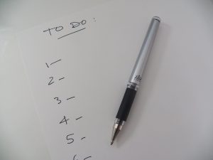 Handwritten to do list with numbers on a pad of paper with a pen sitting on top