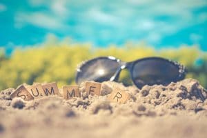 â€œSummerâ€ spelled out in titles in front of sunglasses outside during summer