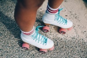 Close up shot of tan legs wearing white roller skates