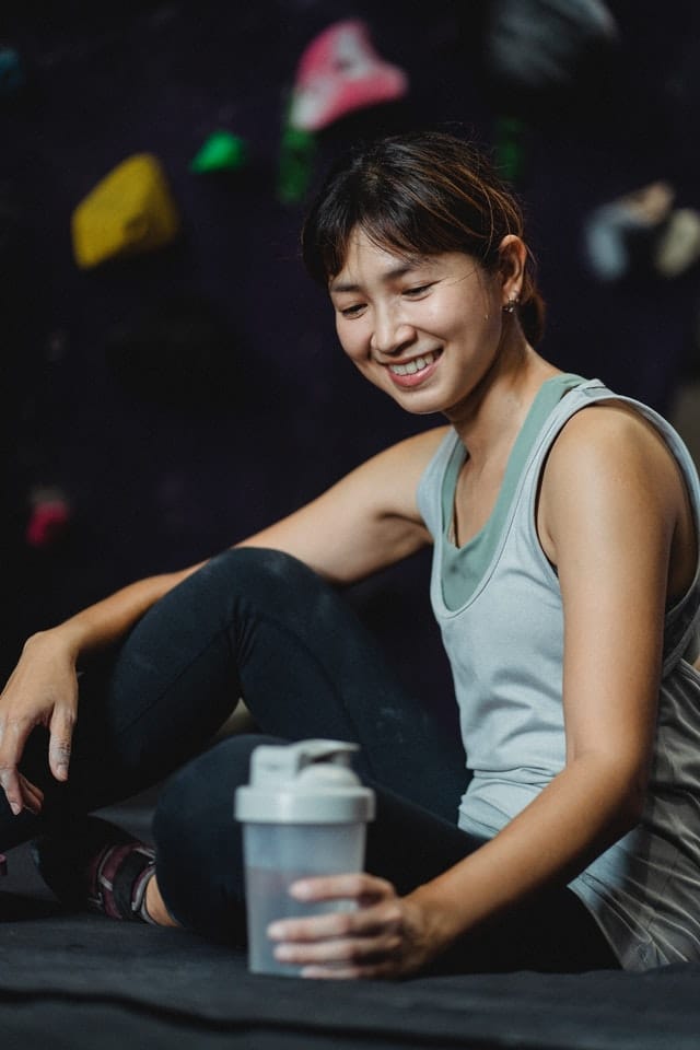 Happy woman in gym resting with bottle of water